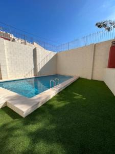 een zwembad met een groen gazon naast een gebouw bij Apto Olta 3 centro Campello piscina wifi parking in El Campello