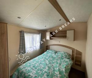 a small bedroom with a bed and a window at Homely 2 bed @ Seal Bay Resort in Selsey