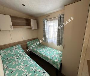 a small room with a bed and a window at Homely 2 bed @ Seal Bay Resort in Selsey
