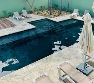 a swimming pool with blue water and two chairs at Résidence Tropic Appart Hotel in Saint-Gilles-les-Bains
