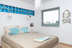 a bed in a white room with a window at Kastelokampos Art House in Patra