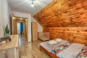 a bedroom with a wooden wall and a bed at Chaty na Skalistym Wzgórzu in Solina
