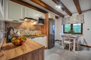 a kitchen with white cabinets and a table with a bowl of fruit at Chaty na Skalistym Wzgórzu in Solina