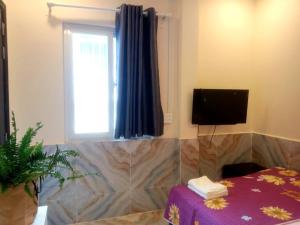 een kamer met een tafel, een televisie en een raam bij An Chi Hotel in Ho Chi Minh-stad