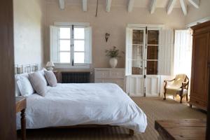 a bedroom with a white bed and a chair at Casa La Siesta in Vejer de la Frontera