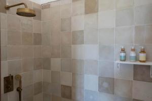 y baño con ducha y pared de azulejos. en Casa La Siesta en Vejer de la Frontera