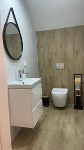 a bathroom with a sink and a toilet and a mirror at Oskarówka Kaszuby z balią in Gołubie