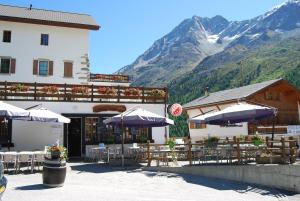 un restaurant avec des tables et des parasols en face d'une montagne dans l'établissement Hotel du Pigne, à Arolla