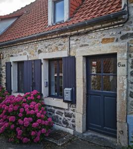 a stone house with a blue door and purple flowers at Maison de pêcheur Wissant plein centre in Wissant