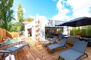 patio con sedie e ombrellone su una terrazza in legno di Villa de luxe au Pyla avec piscine en bordure du golf d'Arcachon, 5 chambres a La Teste-de-Buch