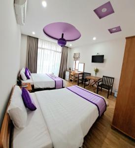 2 camas en una habitación de hotel con techo púrpura en Ms Tri Homestay, en Hoi An