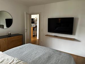 een slaapkamer met een bed en een flatscreen-tv aan de muur bij 2-Zimmer Wohnung in Oberlaa mit privatem Tiefgaragen Platz in Wenen