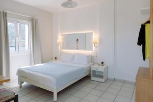 a white bedroom with a bed and a window at Ormos Atalia in Balíon