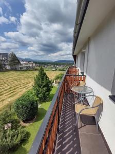 a balcony with a table and chairs and a field at Pokoje Goscinne U Janki in Murzasichle
