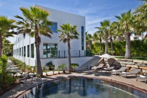 a swimming pool with chairs and palm trees in front of a building at Sao Rafael Holidays in Albufeira