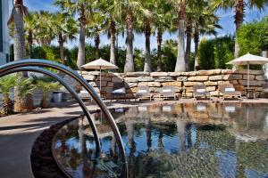a swimming pool with chairs and a stone wall and palm trees at Sao Rafael Holidays in Albufeira