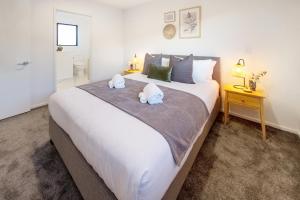 a bedroom with a large white bed with towels on it at Modern Comforts 2 bed 2 bath Inner City in Christchurch