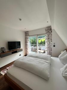 a white bedroom with a large bed and a window at Hotel Hollweger in Sankt Gilgen