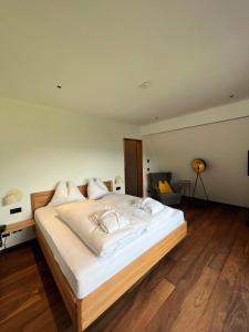 Cama blanca grande en habitación con suelo de madera en Hotel Hollweger en Sankt Gilgen