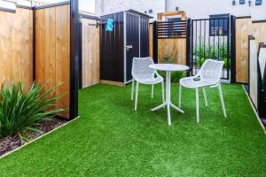 une petite arrière-cour avec de l'herbe verte, une table et des chaises dans l'établissement Modern Comforts 2 bed 2 bath Inner City, à Christchurch