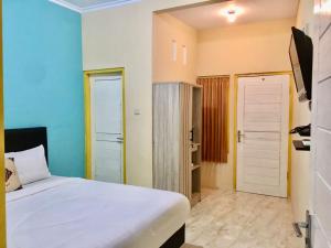 a bedroom with a white bed and a door at GRAND KHALIFAH Guesthouse in Sumbawa Besar