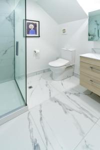 La salle de bains blanche est pourvue d'une douche et de toilettes. dans l'établissement Modern Comforts 2 bed 2 bath Inner City, à Christchurch