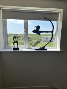 a window with a sculpture of a woman in the window at Entire cosy home from home country retreat in Holyhead
