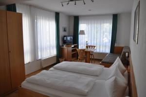 a bedroom with two beds and a table and a desk at Pension Keller in Reichenau