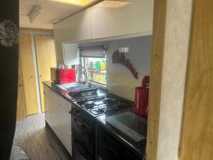 a kitchen with a stove and a counter top at Tracy’s holiday home - static caravan in Hemsby