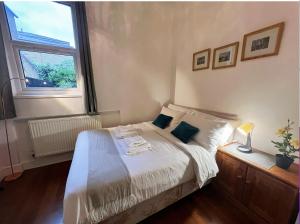 a bedroom with a bed with white sheets and a window at Lovely 2 Bedroom Garden Flat in London in London