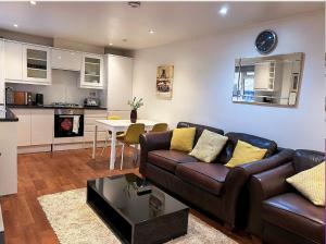 a living room with a brown couch and a kitchen at Lovely 2 Bedroom Garden Flat in London in London