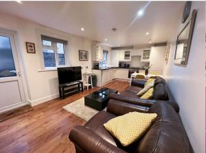 a living room with a brown leather couch and a kitchen at Lovely 2 Bedroom Garden Flat in London in London