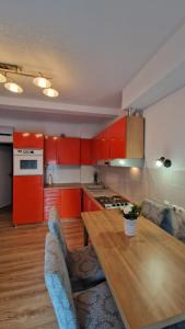 a kitchen with red cabinets and a wooden table at Apartman SKY 4 in Brčko