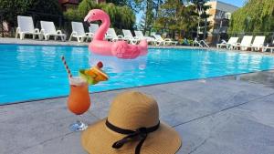 un cappello di paglia e un drink accanto alla piscina di Ośrodek Promenada- Puchatek a Jastrzębia Góra