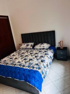 uma cama com um edredão azul e almofadas em Appartement luxueux à Agdal près de la gare em Rabat