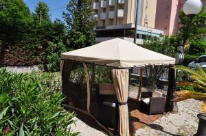 parasolka w ogrodzie z krzesłami pod nim w obiekcie Esedra Hotel w Rimini