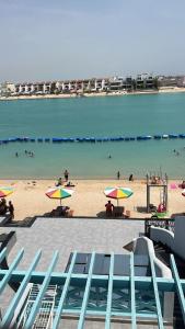 a beach with chairs and umbrellas and people in the water at درة العروس استوديو على شاطئ البرادايس - عوائل in Durat Alarous