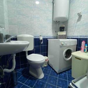 a bathroom with a toilet and a sink and a washing machine at Family friendly home w/ Free Parking & fast WiFi in Skopje