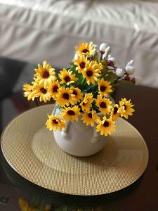 スコピエにあるFamily friendly home w/ Free Parking & fast WiFiのテーブルの上に黄色い花が咲き誇る白い花瓶