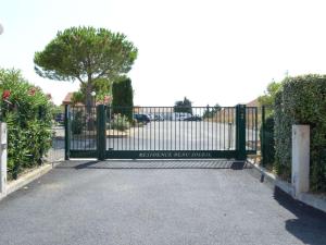 um portão numa entrada com arbustos e árvores em Maison Narbonne, 3 pièces, 5 personnes - FR-1-229B-94 em Narbona