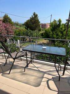a glass table and two chairs on a balcony at Koulouras Holiday Apartments in Nikolaíika