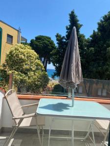 un ombrello seduto su un tavolo con una sedia di Diano Design&Suite Azur a Diano Marina