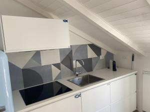 a kitchen with a sink and a geometric wall at Diano Design&Suite Azur in Diano Marina +25 photos