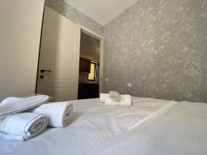 - une chambre avec un lit blanc et des serviettes dans l'établissement Apartment Nizami Kutaisi, à Koutaïssi