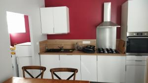uma cozinha com armários brancos e uma mesa com cadeiras em LePireau fr Gîte Maître Futuroscope Piscine chauffée em Vouneuil-sur-Vienne
