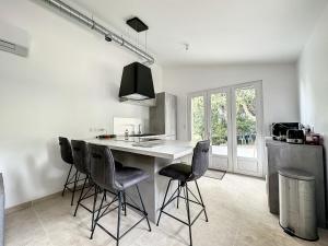 a kitchen with a white counter and black chairs at Villa 2 chambres avec jacuzzi in Bonifacio