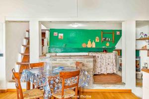 une salle à manger avec une table et un mur vert dans l'établissement Casa Giulia, Trekking and Nature, à Campiglia Marittima