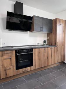 uma cozinha com armários de madeira e um forno preto em Modern und Rustikal mit Kamin Ferienwohnung Kohlert em Bad Berleburg