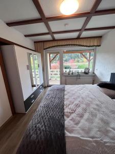1 dormitorio con cama grande y ventana grande en Modern und Rustikal mit Kamin Ferienwohnung Kohlert, en Bad Berleburg