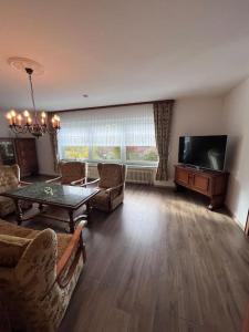 ein Wohnzimmer mit einem Tisch und einem Flachbild-TV in der Unterkunft Modern und Rustikal mit Kamin Ferienwohnung Kohlert in Bad Berleburg